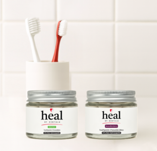 Two jars labeled 'heal' with a toothbrush on a tiled bathroom wall background.