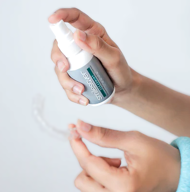 Hand holding a spray bottle labeled 'Squissit' against a white background